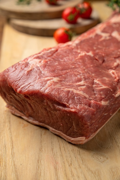 Morceaux de viande crue de boeuf aux épices et fines herbes sur une planche de bois