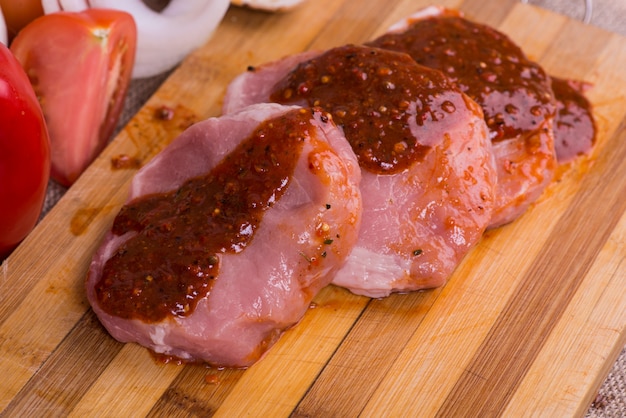 Photo morceaux de viande crue pour barbecue avec des tomates de légumes frais, de la laitue sur une surface en bois.