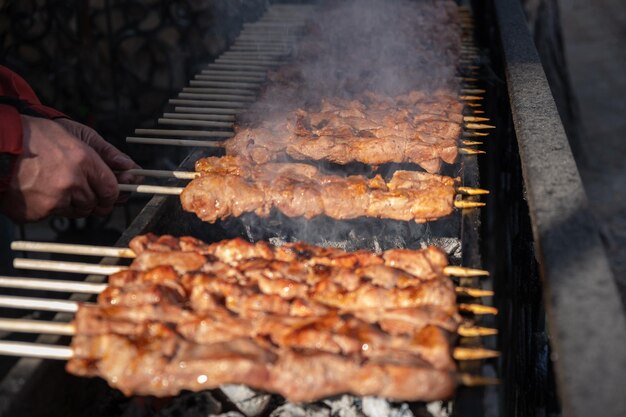 Morceaux de viande enfilés sur des brochettes métalliques sur le grill au coucher du soleil