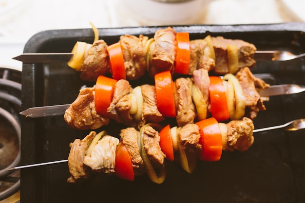 Morceaux de viande hachée crue avec tomates et rondelles d'oignon prêts pour le barbecue