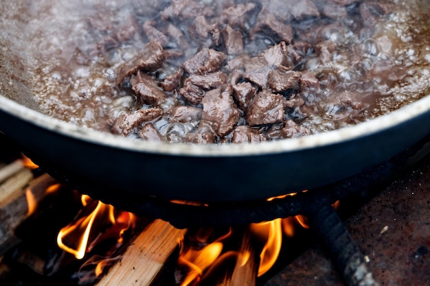 Photo des morceaux de viande pour pilaf sont cuits dans un chaudron sur un feu de joie