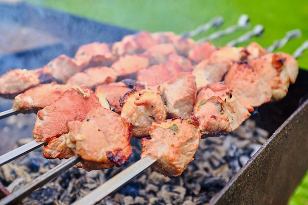 Des morceaux de viande sont frits sur le feu sur des brochettes