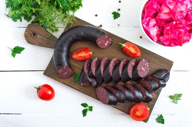 Morcilla - saucisse de sang. Morceaux de boudin noir espagnol sur une planche à découper en bois sur tableau blanc.