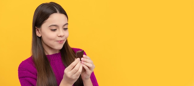 Morsure pleine de bonheur et de joie Enfant heureux manger du chocolat Manger du chocolat Irrésistiblement savoureux Affiche horizontale de l'espace de copie d'en-tête de bannière de visage d'enfant isolé