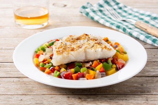 Morue grillée aux légumes dans une assiette sur une table en bois