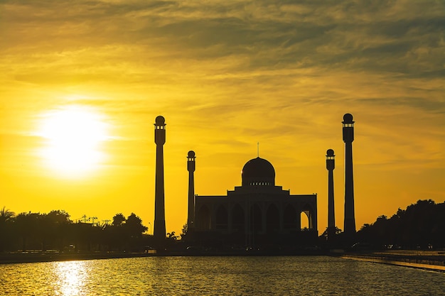 Mosquée centrale de Songkhla de jour comme de nuit avec un ciel coloré au coucher du soleil et les lumières de la mosquée et des reflets dans l'eau dans un concept de paysage emblématique