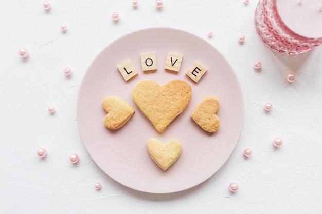 Mot d&#39;amour et biscuits en forme de coeur sur une assiette rose