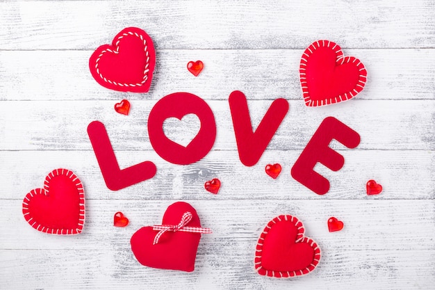 Mot amour et coeurs rouges sur une table en bois blanc. Lettres textiles rouges. Carte de voeux Saint Valentin