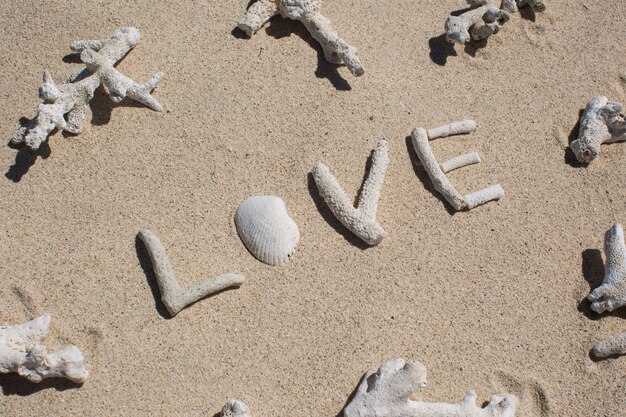 Mot d'amour des coraux sur le sable de la plage tropicale