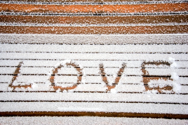 Le mot AMOUR écrit dans la neige sur un banc dans un parc d'hiver