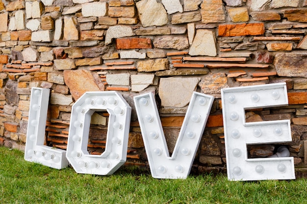 Photo un mot d'amour près du mur de pierre. zone de photo dans la décoration de mariage dans le parc