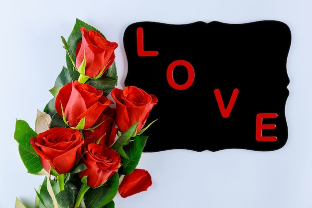 Photo mot d'amour sur tableau noir et bouquet de belles roses rouges. saint valentin ou fête des mères.