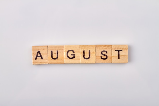 Mot d'août écrit sur des blocs de bois. Isolé sur fond blanc.