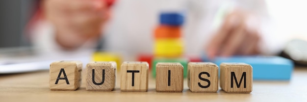 Mot autisme sur des blocs de bois libre et médecin flou avec des blocs multicolores et des jouets en arrière-plan Concept de traitement de l'autisme