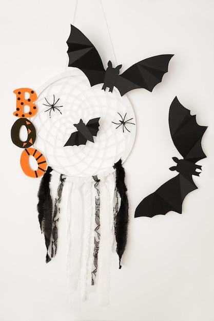 Le mot boo, chauves-souris et un capteur de rêves avec des araignées sur fond blanc est un concept d'Halloween.