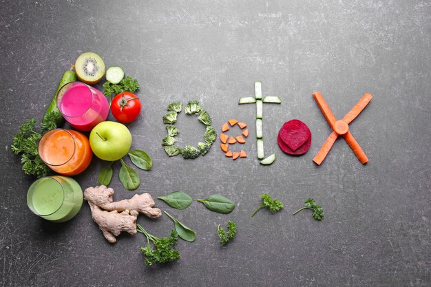 Photo mot detox composé de jus de légumes frais dans des verres et d'ingrédients sur fond gris