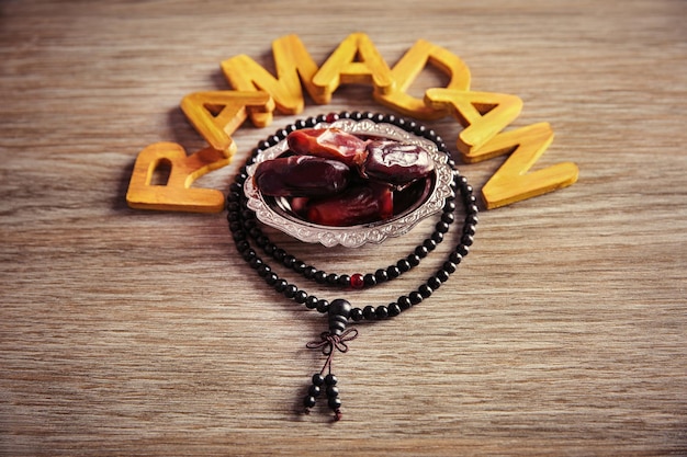 Mot du ramadan avec chapelet de lettres en bois et dates sèches sur la table