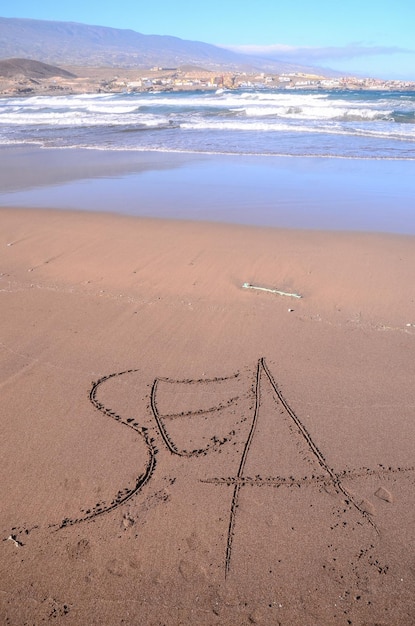 Mot écrit sur le sable d'une plage tropicale