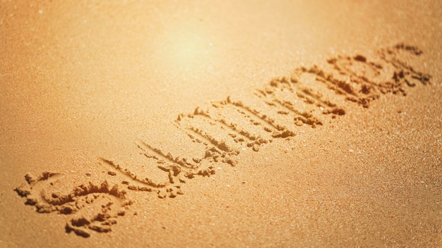 Le mot été est écrit sur le sable jaune de la plage.