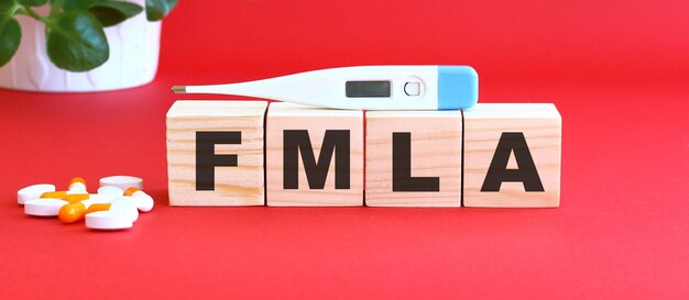 Le mot FMLA est fait de cubes en bois sur une surface rouge avec des médicaments.