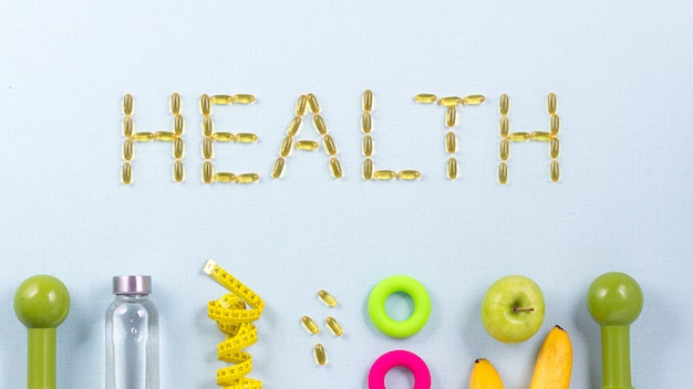 Le mot HEALTH est écrit avec des capsules d’oméga 3 entourées d’équipement sportif,