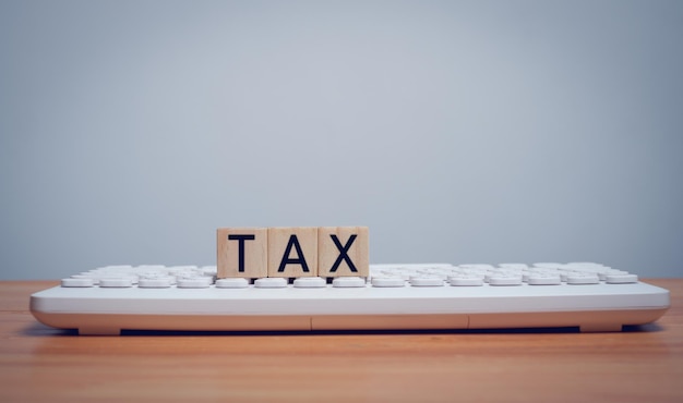 Mot d'impôt sur un bloc de bois qui est placé sur le concept de clavier du concept d'entreprise de remplissage d'impôt en ligne
