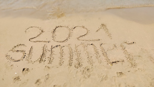 Mot manuscrit été 2021 sur la plage de sable jaune. vacance