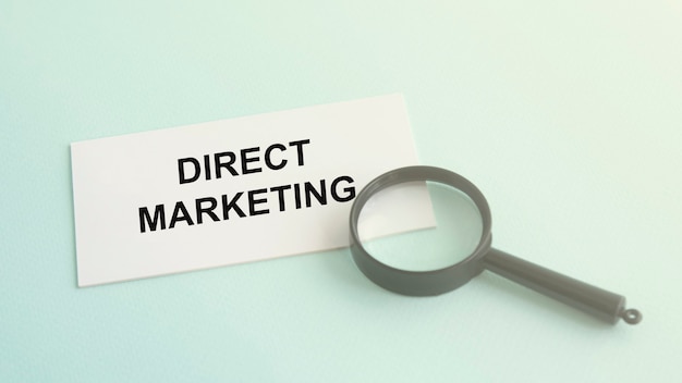 Mot de marketing direct sur carte papier blanc et loupe