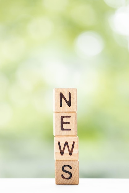 Le mot NEWS est écrit sur des cubes en bois sur un fond d'été vert Gros plan d'éléments en bois