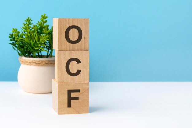Mot OCF à partir de blocs de bois avec des lettres concept d'entreprise sur fond bleu copie espace disponible Abréviation OCF pour flux de trésorerie d'exploitation