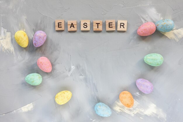 Mot de Pâques et décoration d'oeufs de couleur pastel et or sur fond gris Célébration de Pâques