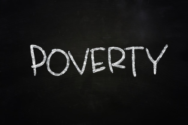 Photo le mot pauvreté écrit à la craie sur le tableau noir