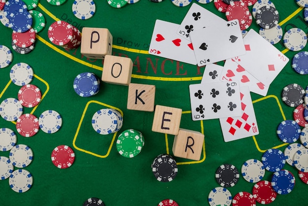 Le mot poker sur des cubes en bois jetons de poker avec des cartes à jouer sur la table de casino verte pari