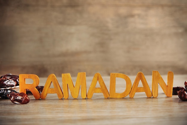 Photo le mot ramadan avec des lettres en bois et des dattes sèches sur la table