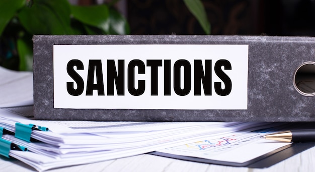 Le mot SANCTIONS est écrit sur un dossier gris à côté des documents