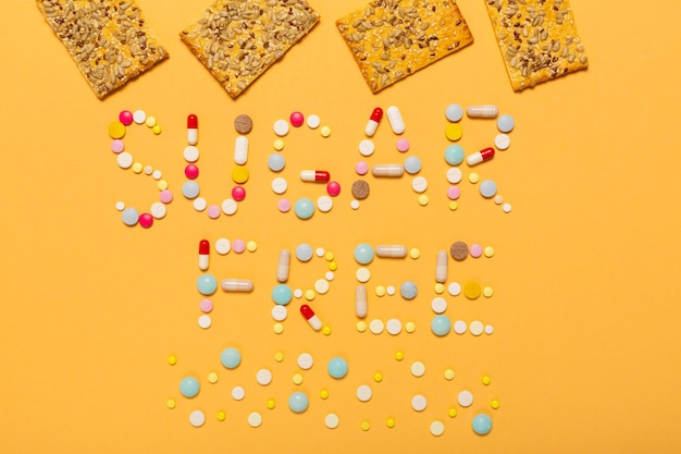 Un mot sans sucre est écrit avec des pilules colorées et des biscuits de repas sains avec des graines