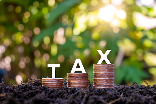 Photo le mot taxe sur une pile de pièces sur le sol concepts pour la planification des réductions d'impôts dépenses comptabilité tva impôt sur le revenu et calculs fiscaux