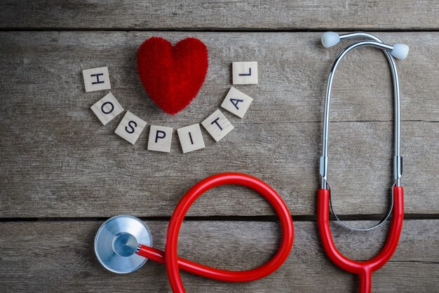 Photo mot de texte de l'hôpital fait avec des blocs de bois et coeur rouge, stéthoscope sur table en bois