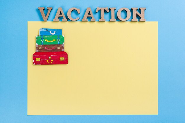 Mot de vacances abstrait lettres en bois. Bleu jaune, image de tas de valises, espace copie