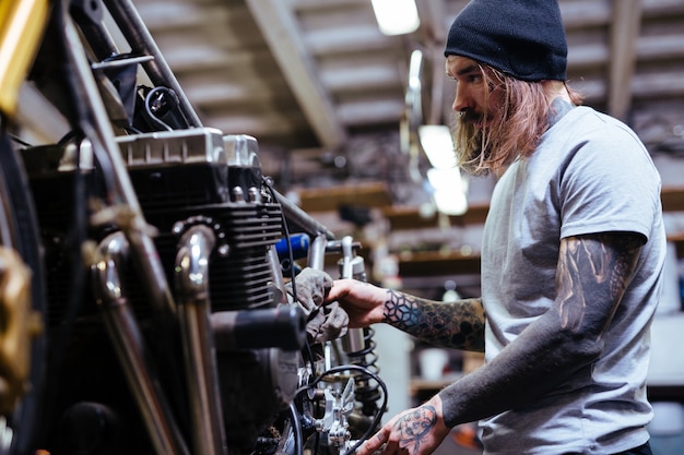 Motard tatoué fixation moto dans l&#39;atelier