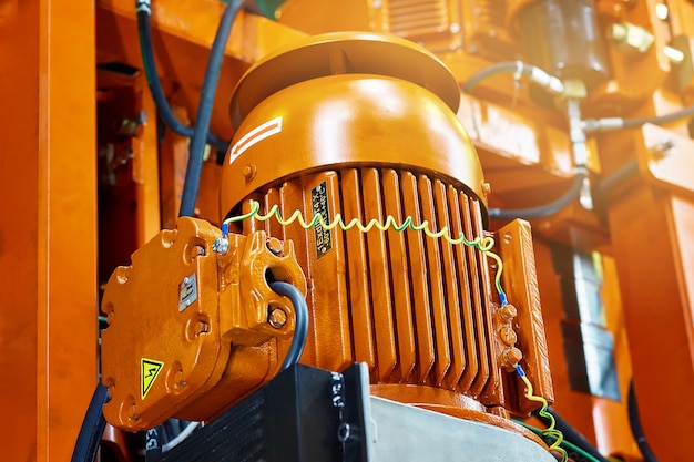 Moteur électrique orange avec fils et tuyaux sur le fond d'une construction lourde