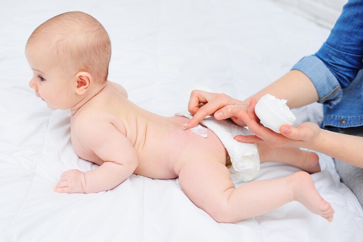 Photo mothers hand applique une crème hydratante pour bébé sur l'hygiène de la peau du bébé garçon du nouveau-né