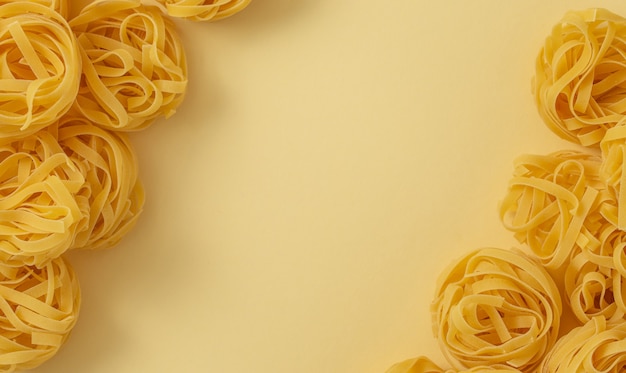 Motif alimentaire minimal de tagliatelles de pâtes, fond pastel jaune clair avec un espace pour le texte. Pâtes italiennes traditionnelles dans un style pop art, concept de cuisine italienne. Vue de dessus, mise à plat, espace de copie