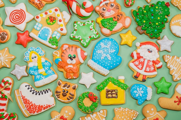 Motif de biscuits colorés en pain d'épice de différentes formes sur la surface verte. Mise à plat. Joyeux Noël, nouvel an, concept d'hiver.