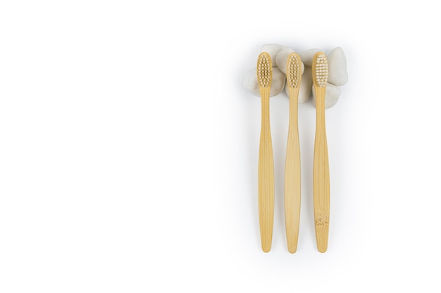 Motif de brosses à dents en bambou avec des pierres blanches sur fond blanc.