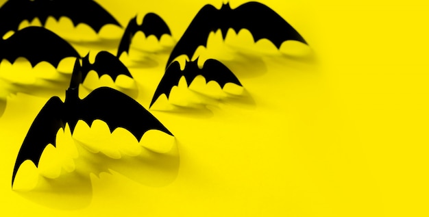 Motif de chauve-souris de papier minimaliste avec ombre tombante sur jaune.