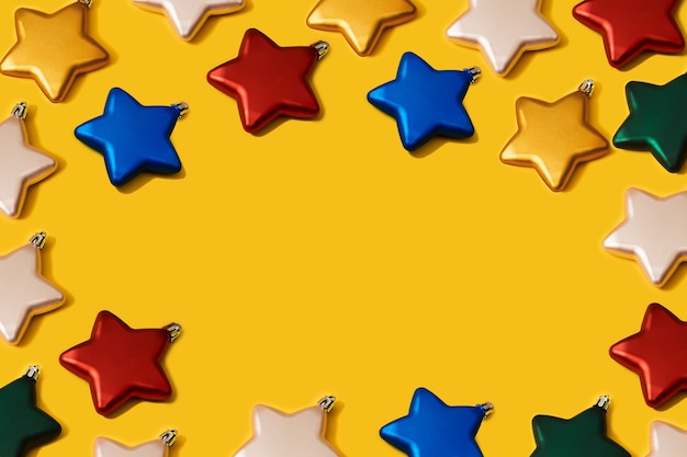 Motif de décoration de boules en forme d'étoile de couleur vibrante de Noël créatif sur fond de papier jaune. Concept minimal de mise à plat du nouvel an avec espace de copie.