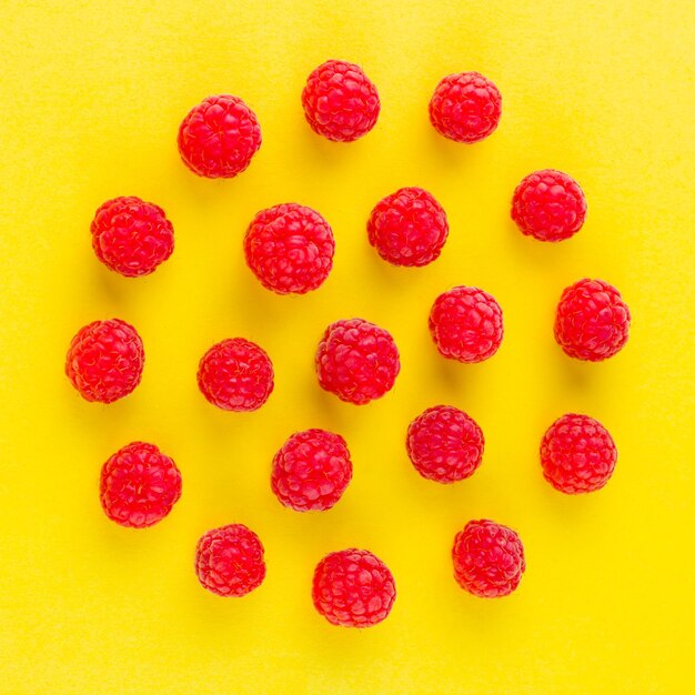 Motif de framboises sur fond jaune Diète colorée et concept d'alimentation saine Vue supérieure