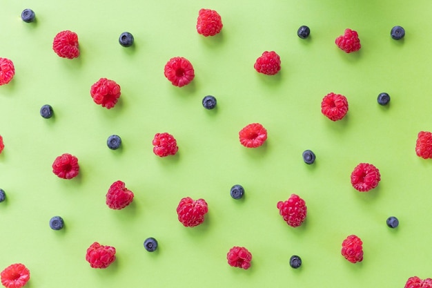 Motif de fruits colorés de baies sauvages sur fond vert Framboises myrtilles Vue de dessus Plat layMotif de baies rouges sucrées mûres Concept d'alimentation saine et diététique