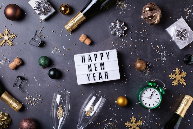 Photo motif de la nouvelle année avec des verres de champagne, des bouteilles, des confettis étincelants, vue d'en haut.